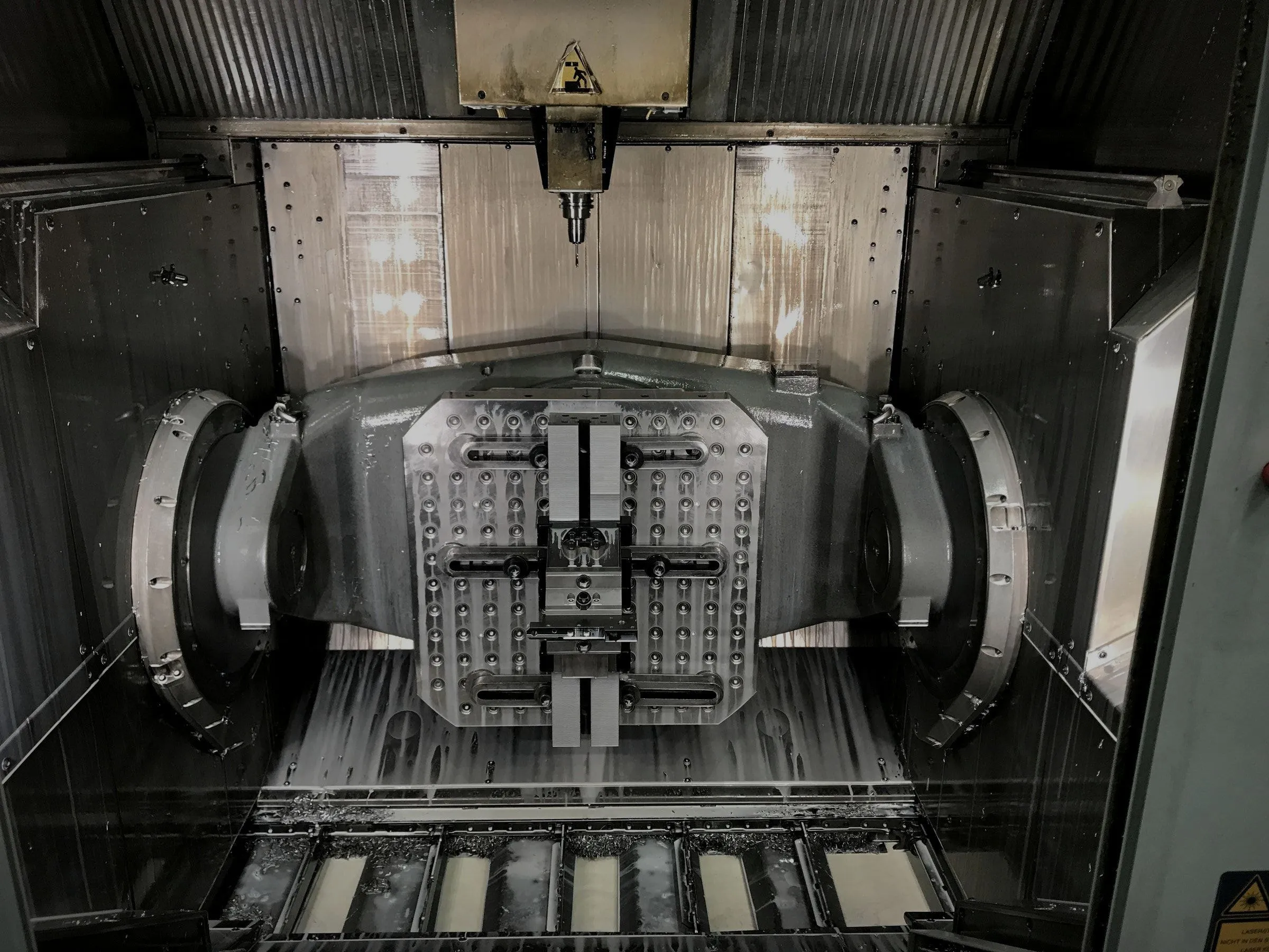 Inside a 5-axis machining center: a tombstone fixture on a trunnion table beneath the spindle.